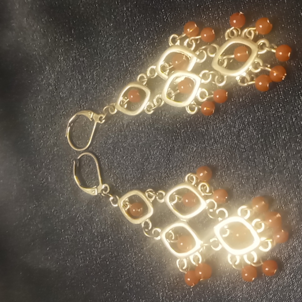 Chandelier earrings with glass beads in gold tone .